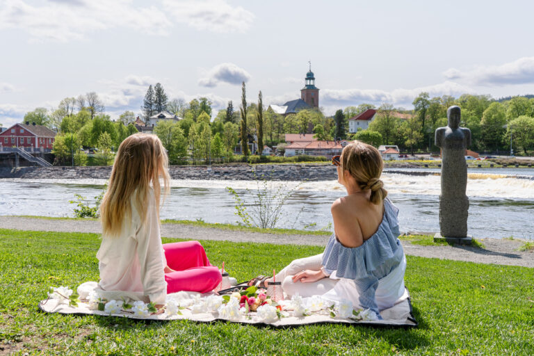 Bilde av 2 jenter som sitter i parken og spiser en piknikk.
