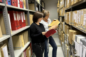 Bilde av to personer som ståer inne i et arkiv.