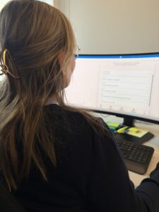 Person foran pc skjerm med Aidn på.